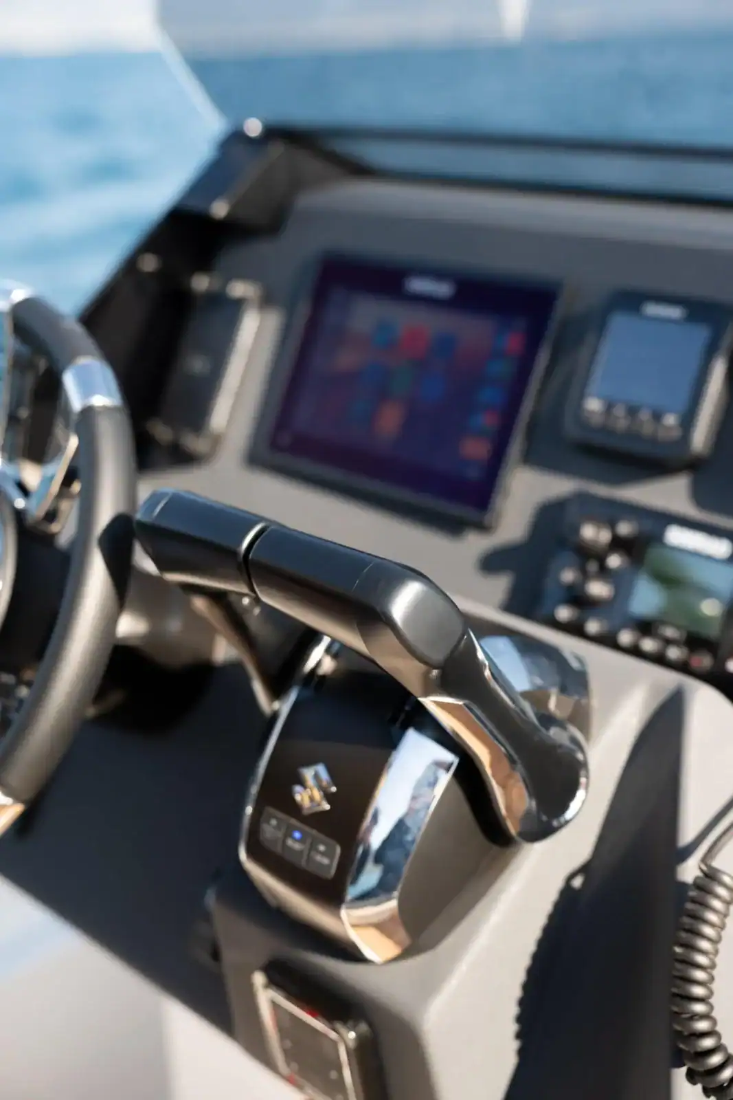 The Technohull GT7 helm console with the throttle, the chartplotter, the VHF radio and the switch panel, open sea beyond