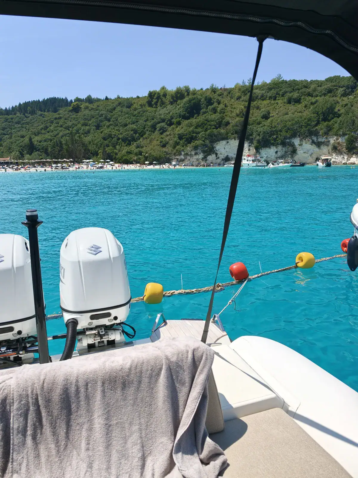 Looking out past Emerald’s stern from beneath the canopy: the two engines, the edge of the bathing platform, turquoise water and a beach beyond